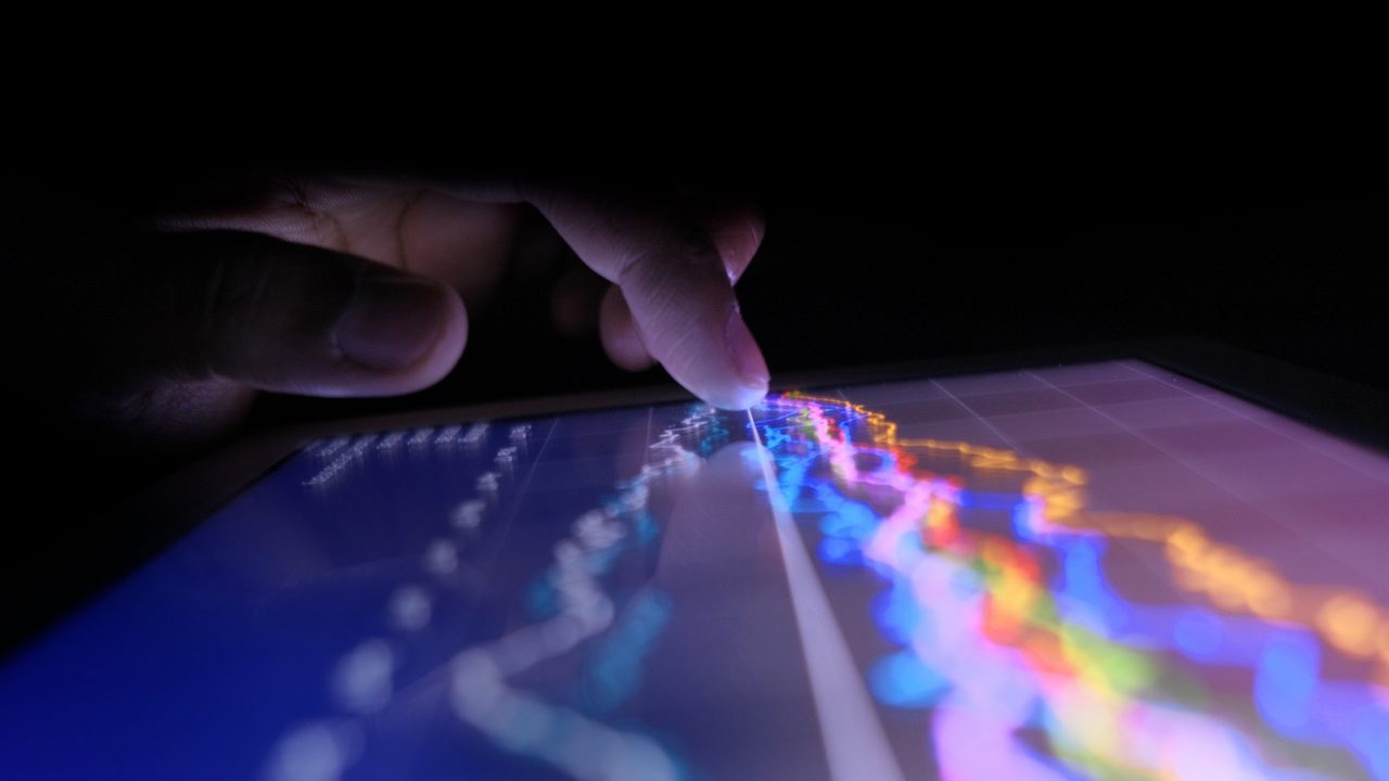 Close up of man hand with digital tablet analyzing stock market graph at night